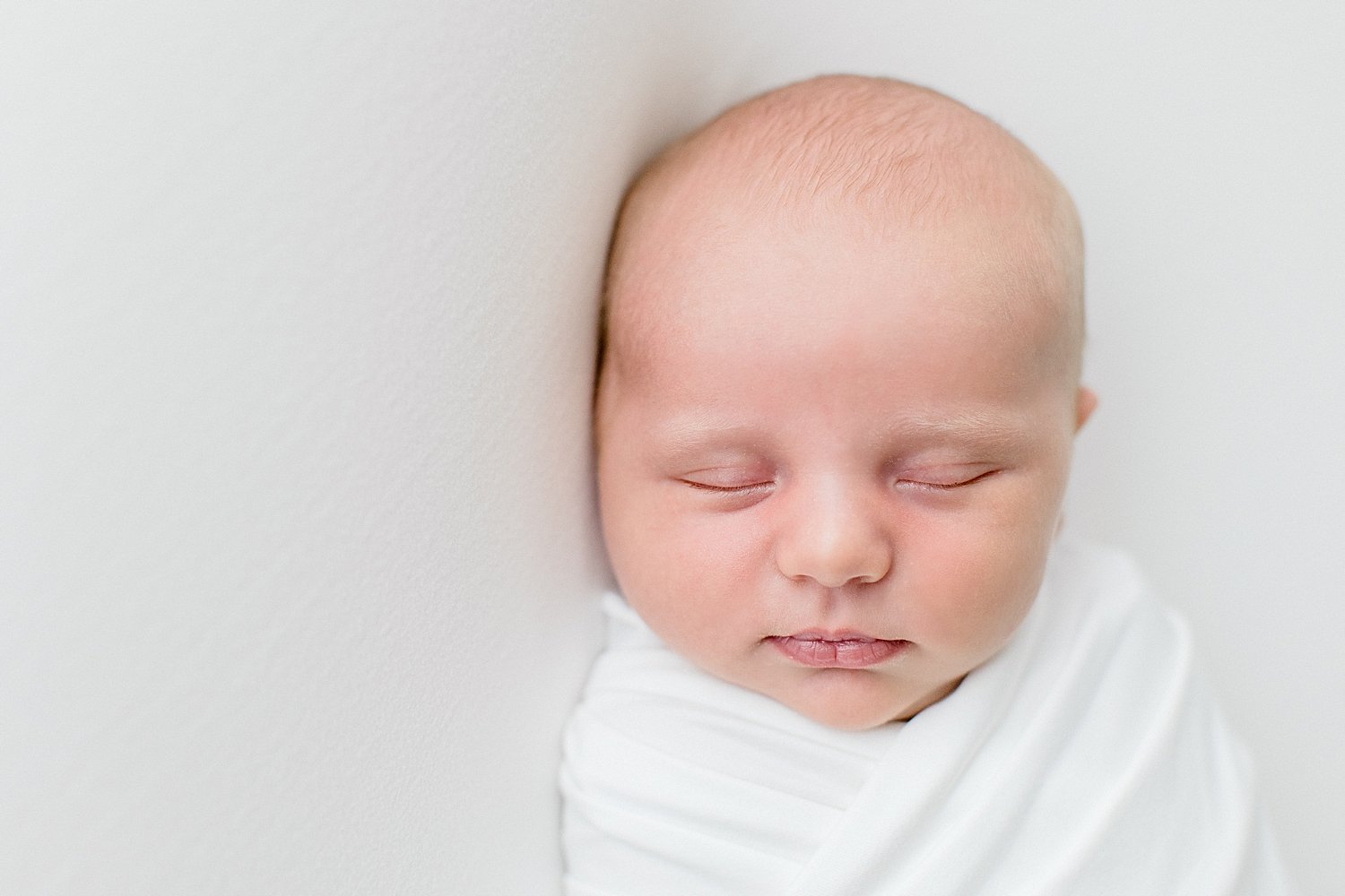 Baby boy swaddled in white at newborn session with Ambre Williams Photography.