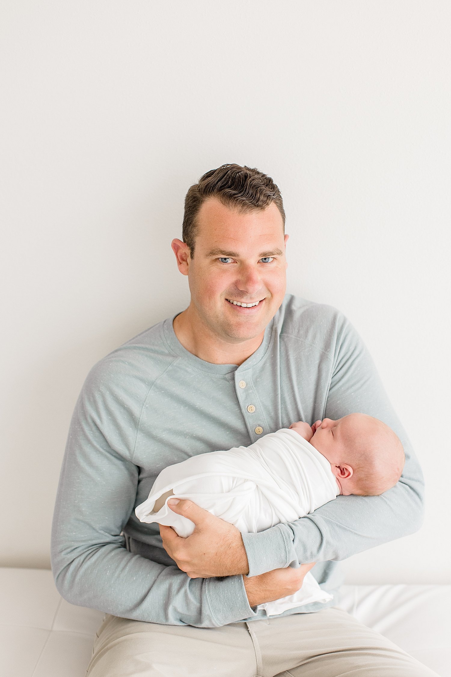 Dad holds newborn son in studio with Newport Beach photographer Ambre Williams Photography. 