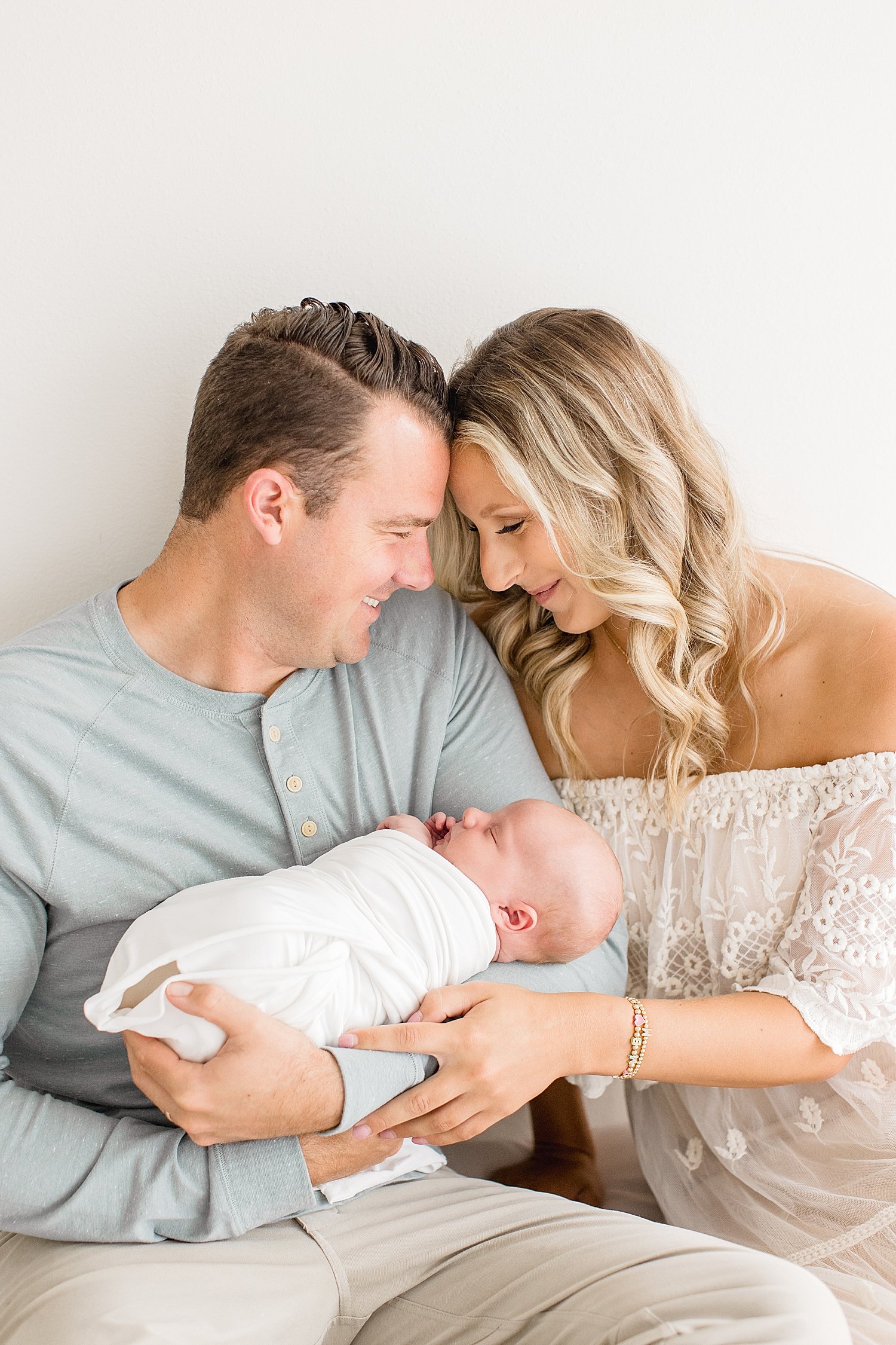 New parents embracing while holding newborn son with Ambre Williams Photography.
