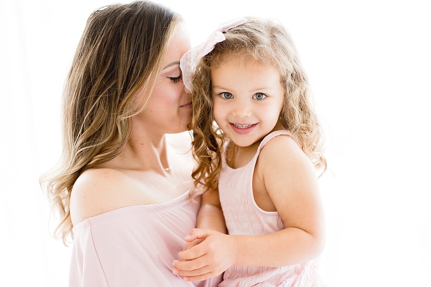 Mom cuddles with daughter in pink dress with Ambre Williams Photography in Newport Beach studio. 