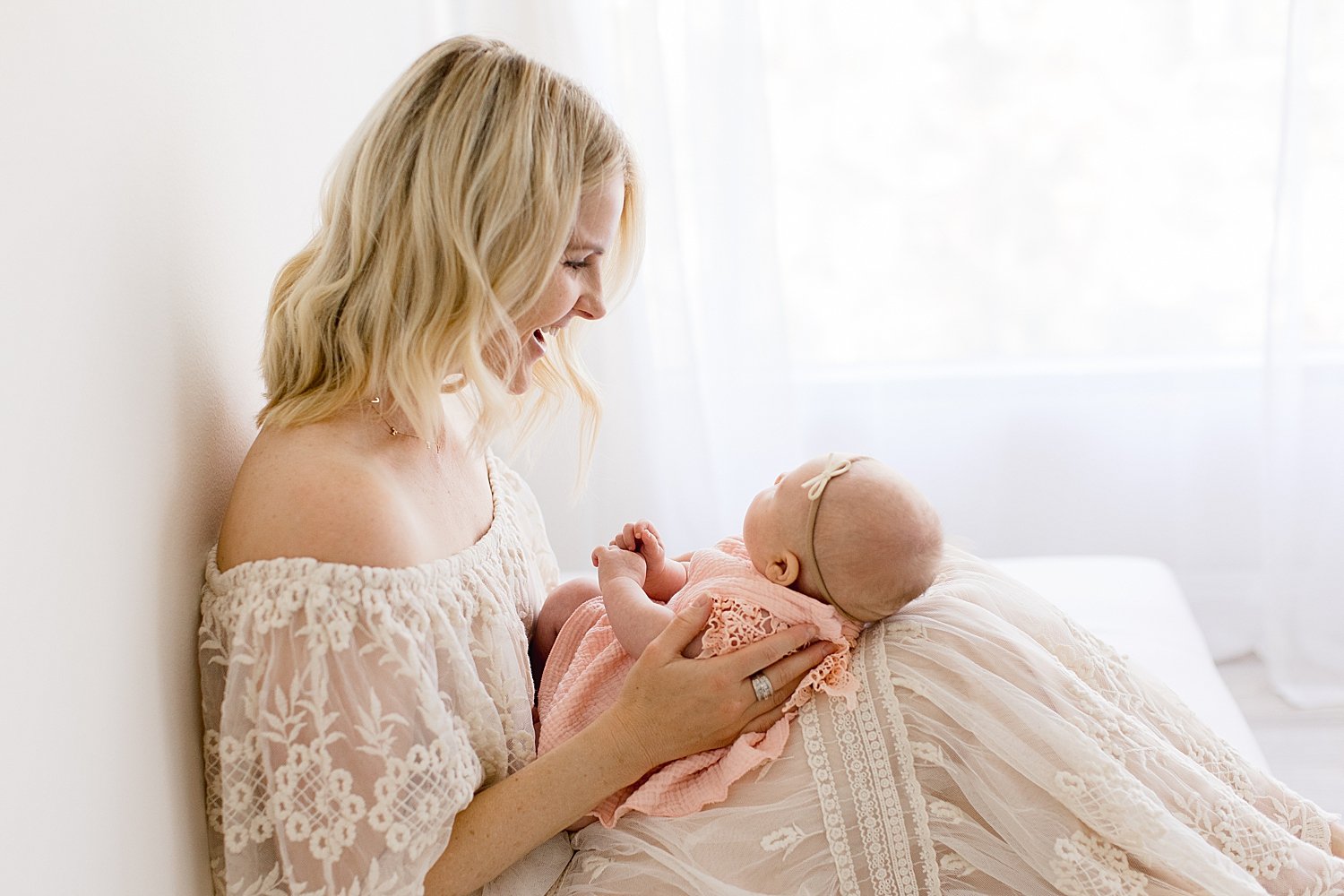 Mom looking down at newborn daughter in Newport Beach Studio with Ambre Williams Photography
