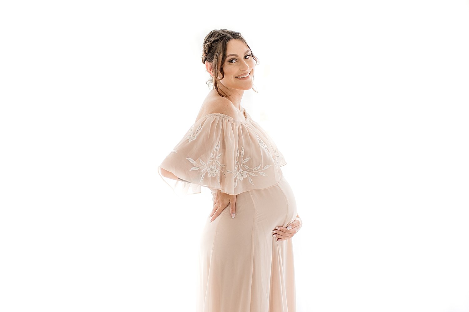 Smiling pregnant mother in long dress holding her belly for maternity session in Newport Beach with photographer Ambre Williams