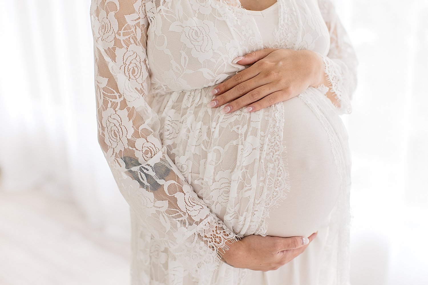 Pregnant mother holding her stomach in white lace dress | Ambre Williams Photography