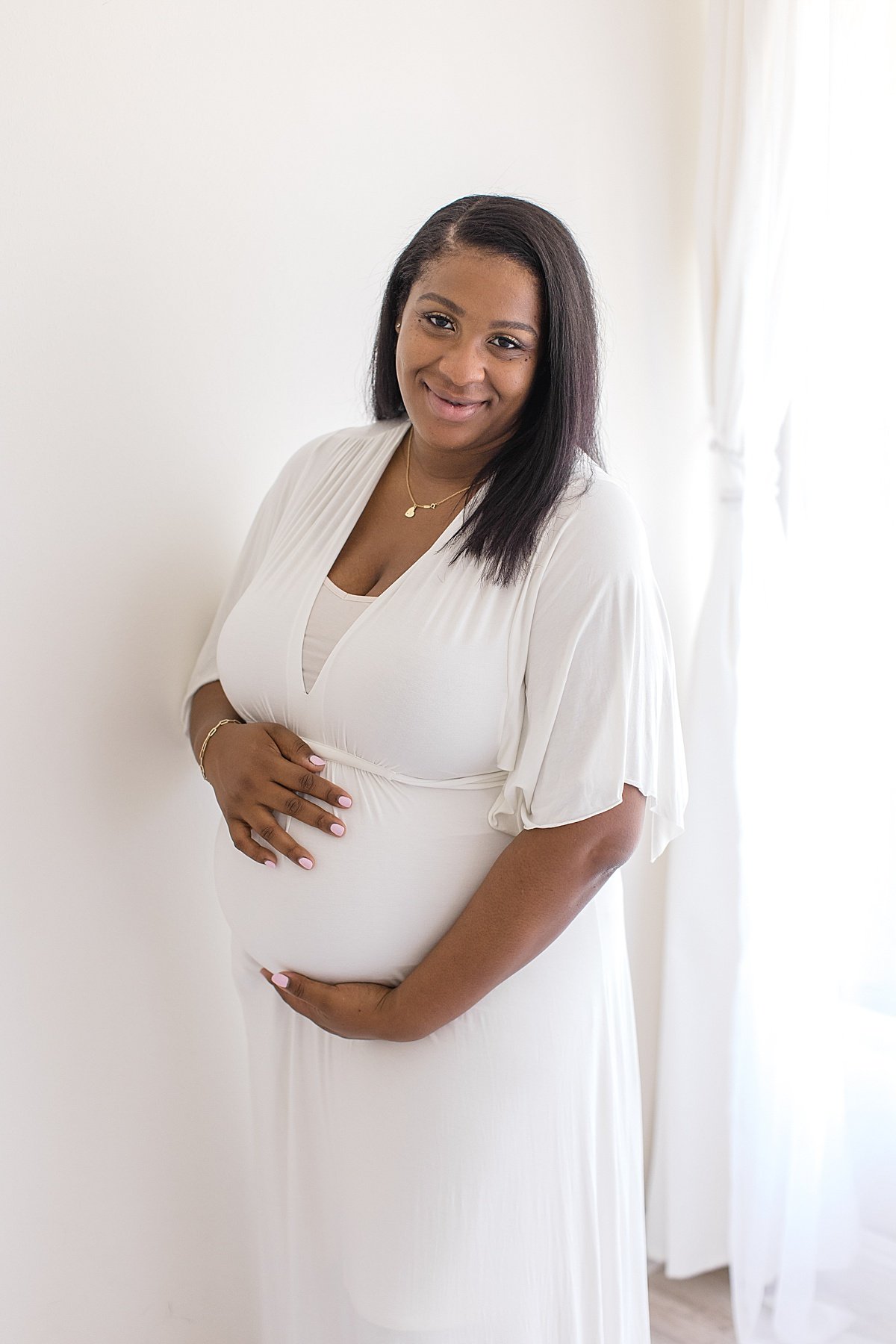 Beautiful Mama holding her pregnant belly during maternity studio session in Newport Beach with Ambre Williams Photography