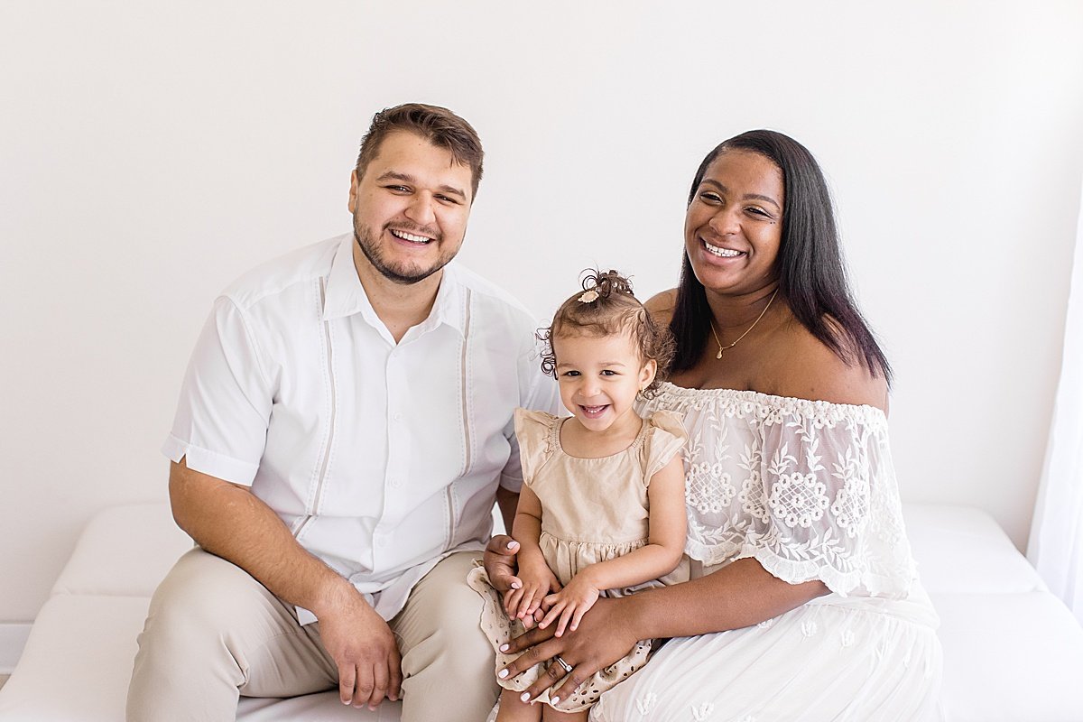 Family smiling together on couch during Maternity Session with Ambre Williams in her studio in Newport Beach