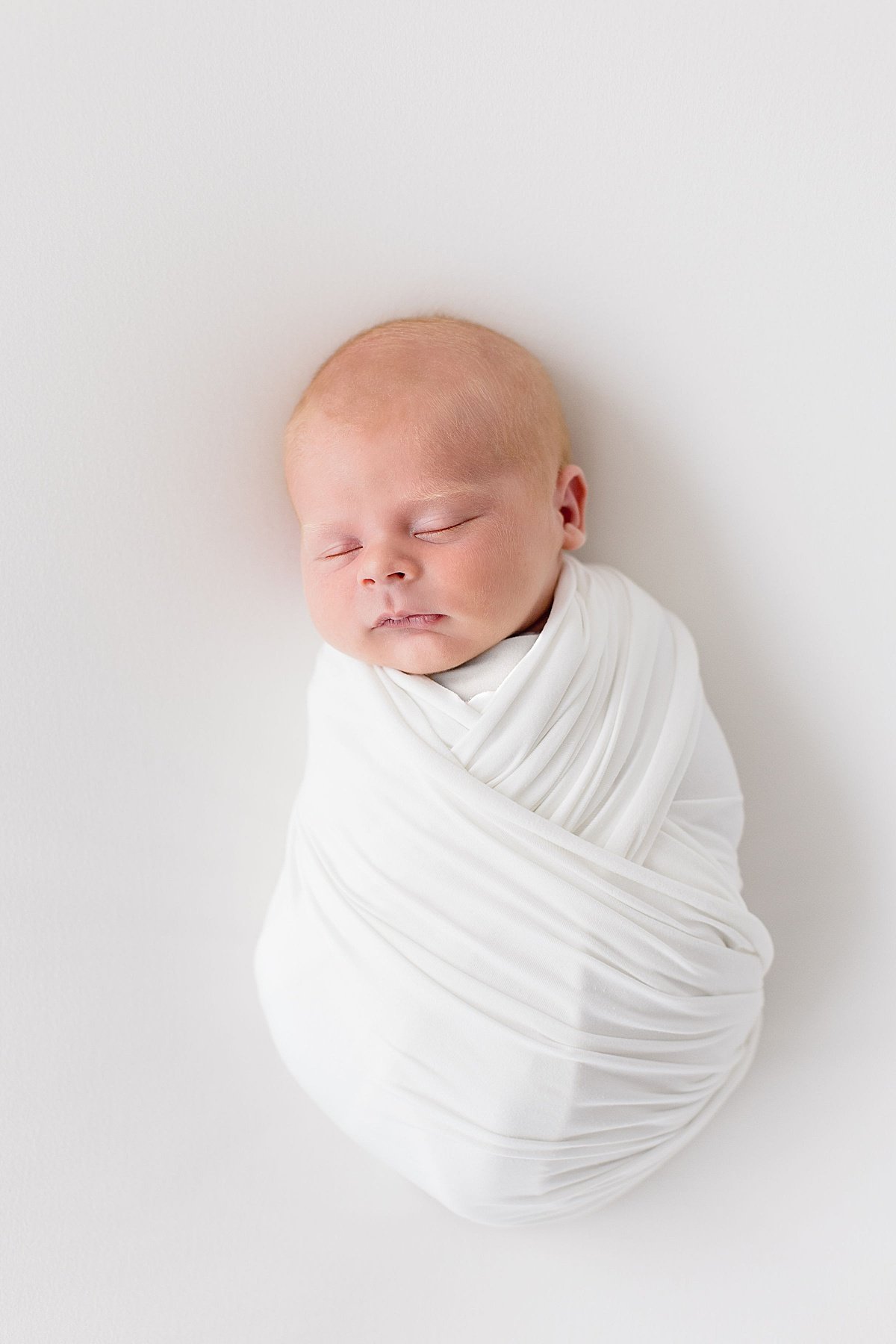 baby buddled up in swaddle during newborn studio session with Ambre Williams Photography in Newport Beach