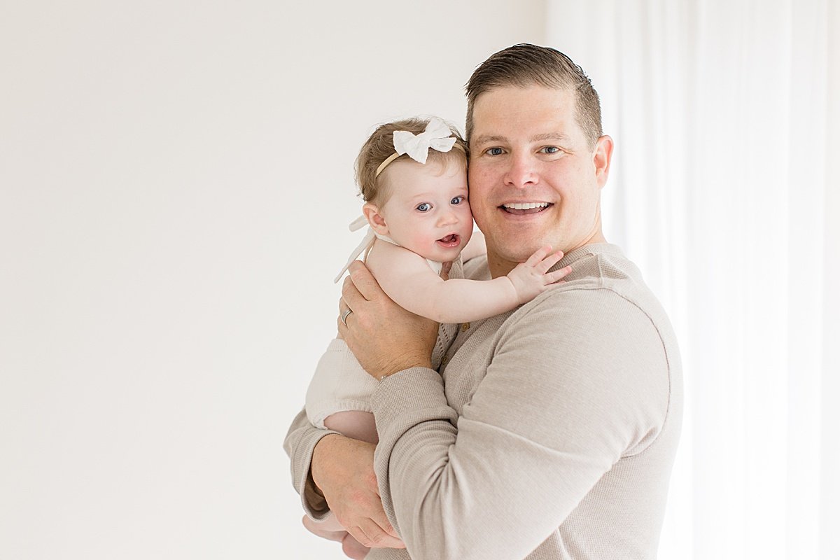 Dad carrying 6-Month old daughter in a studio session with Ambre Williams in Huntington Beach