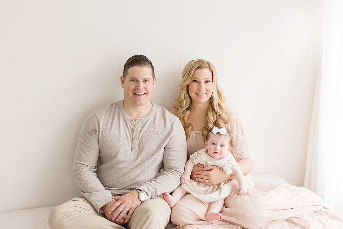 Mom and Dad holding little 6-month old daughter during a milestone session with Ambre Williams Photography in Newport Beach