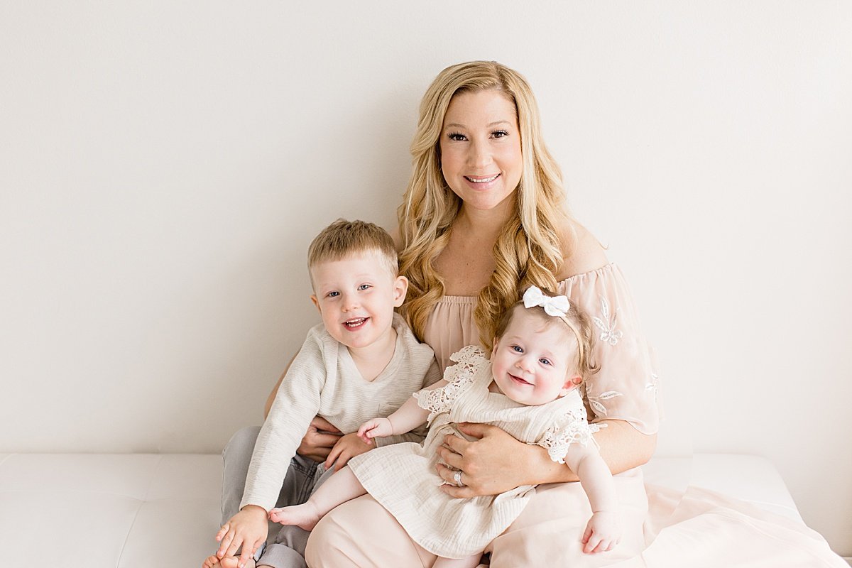Mom holding her two young children during a milestone studio session in Newport Beach with Ambre Williams Photography