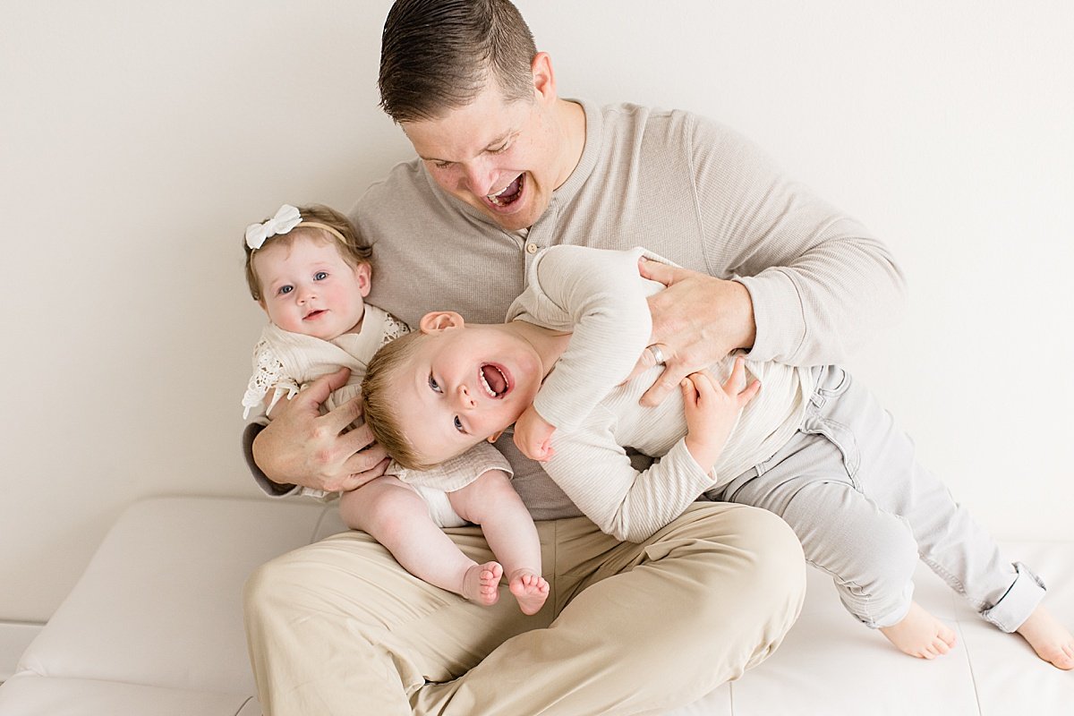 Candid Portrait of dad holding his two children, older brother and little sister | Ambre Williams Photography in Newport Beach