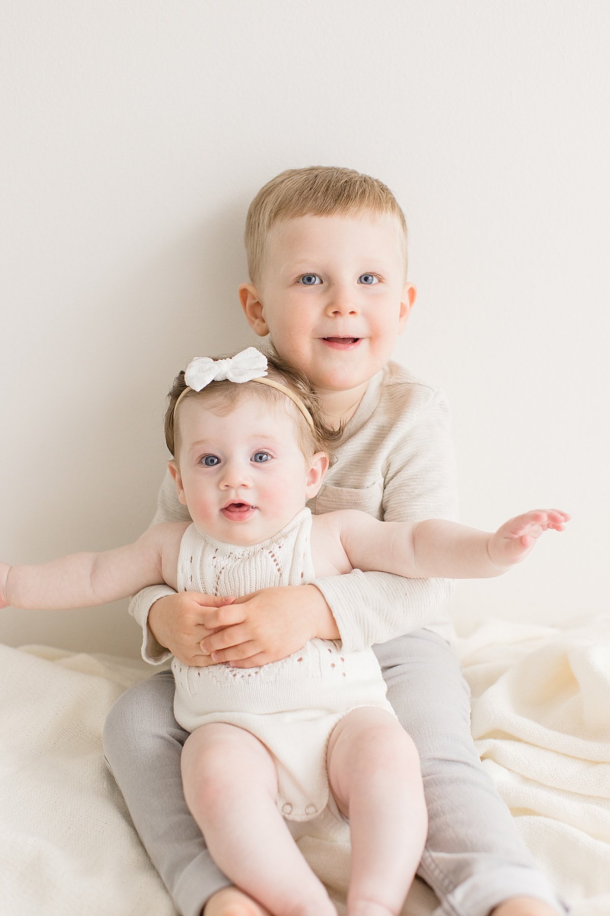 Ambre Williams Photography takes photos of Big brother holding younger sister in studio session in Newport Beach