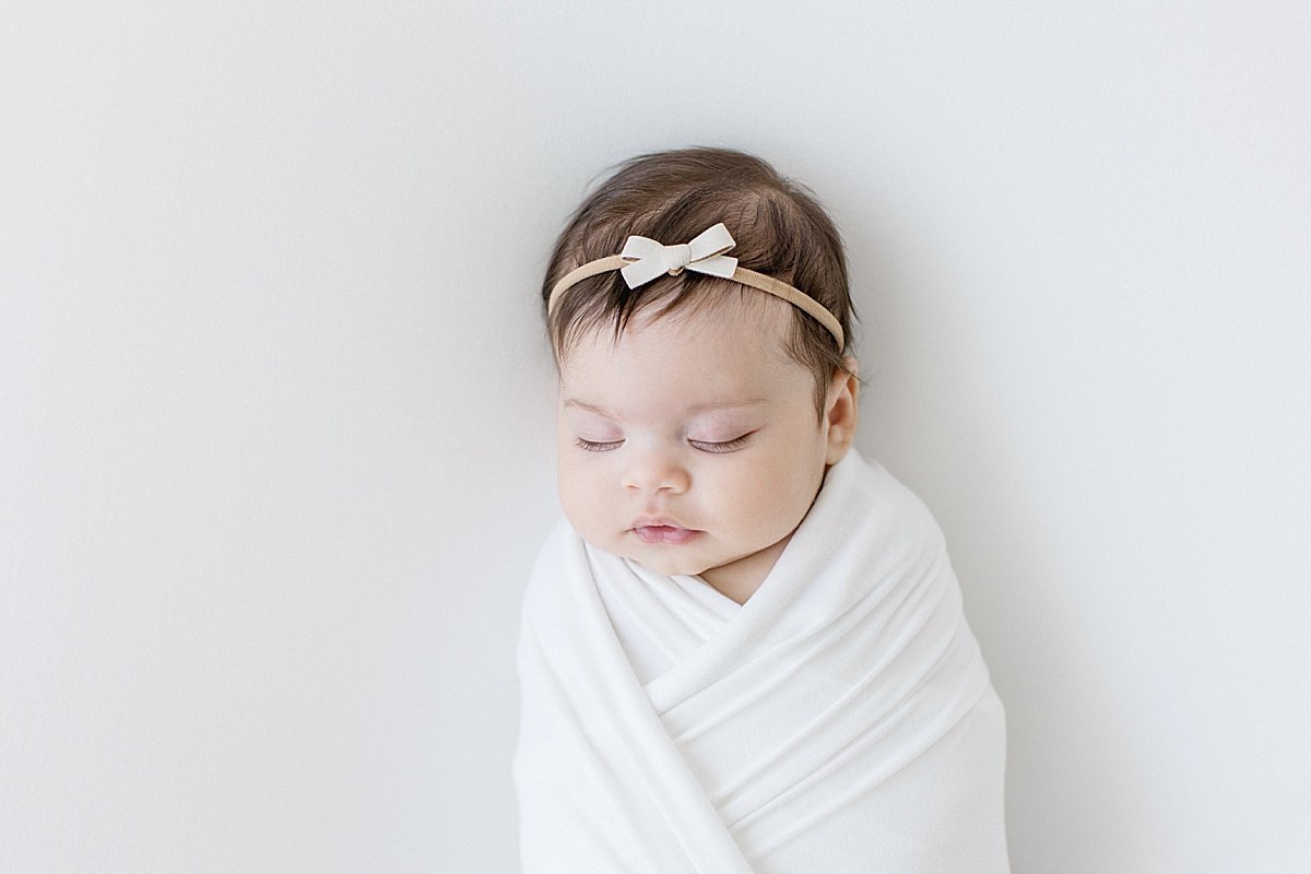 Sleepy newborn daughter swaddled up during studio session with Ambre Williams in her Newport Beach Studio
