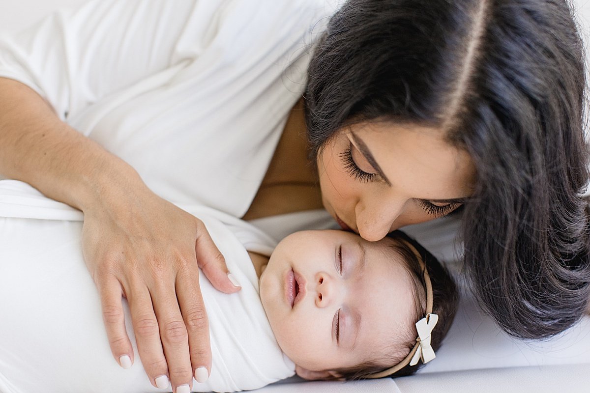 Sweet Little Kisses from Mama to Daughter during Newborn Session in Newport Beach, CA with Ambre Williams Photography