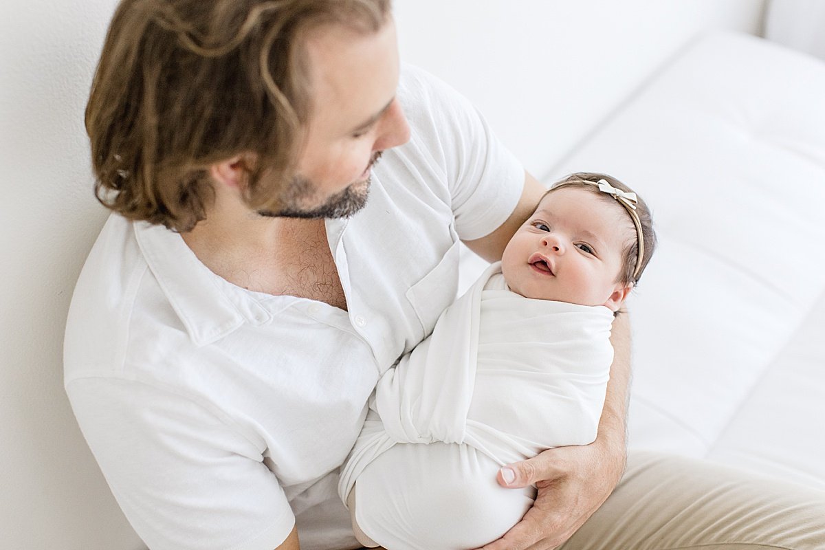 New Dad holding his daughter swaddled in white blanket  | Newport Beach Photographer Ambre Williams