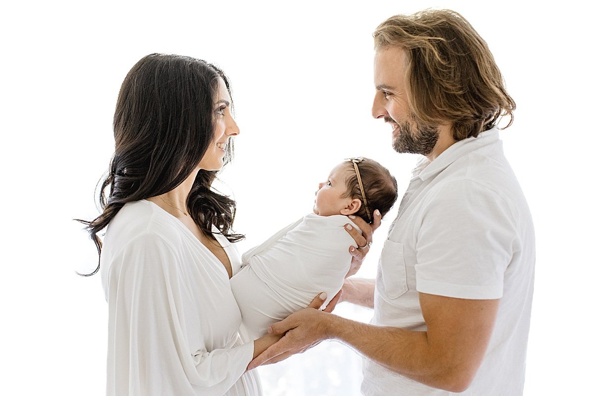 Mom and Dad looking at each other while holding their newborn baby | Ambre Williams Photography Studio in Newport Beach, California