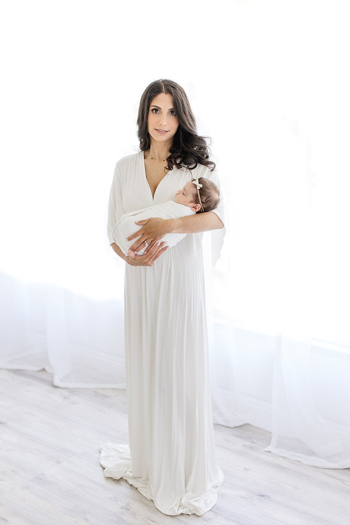 Mom holding Newborn by studio window | Newport Beach Photographer Ambre Williams Photography