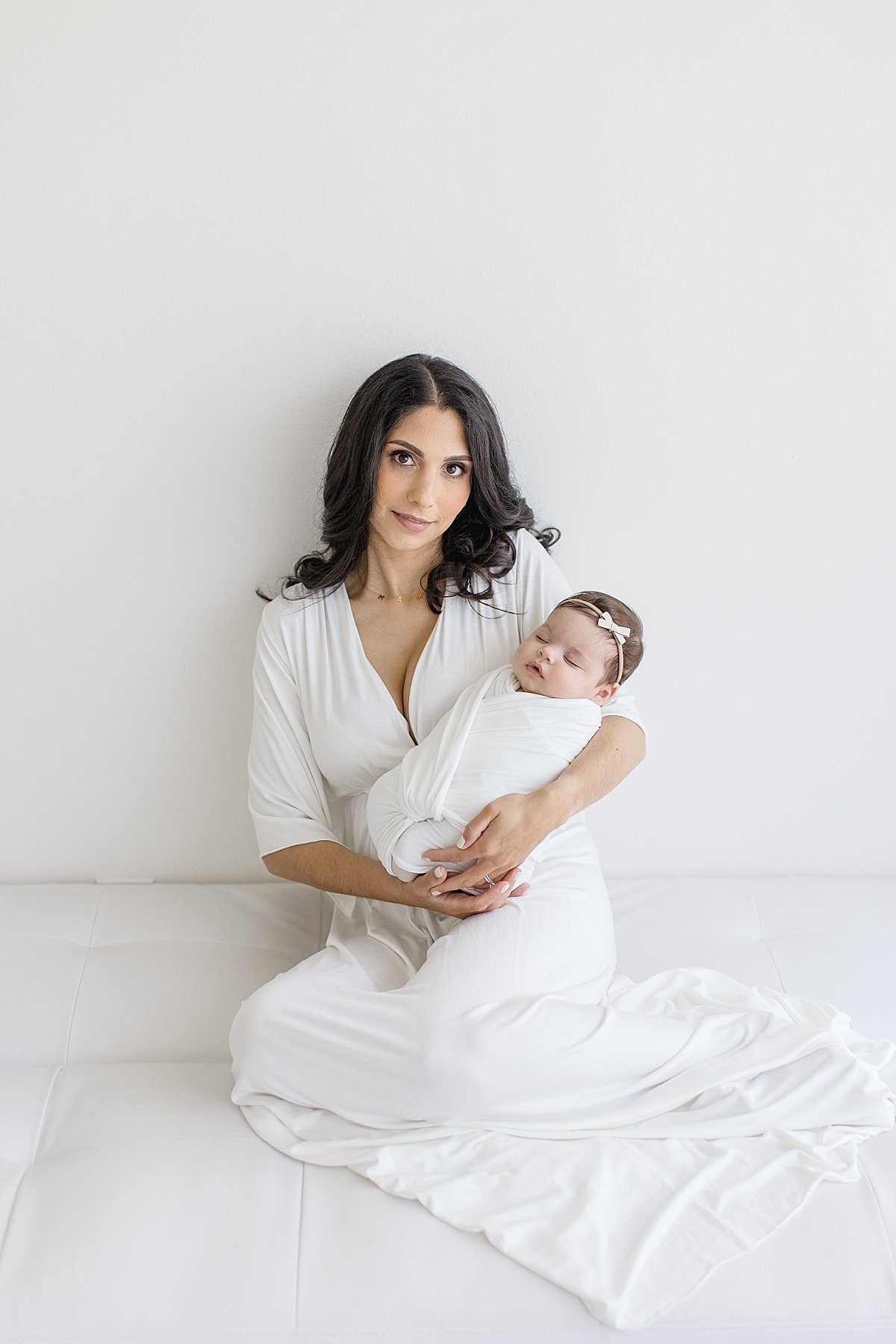 Mom holding sleeping daughter during Newborn Photography Session with Ambre Williams in her studio in Newport Beach, California