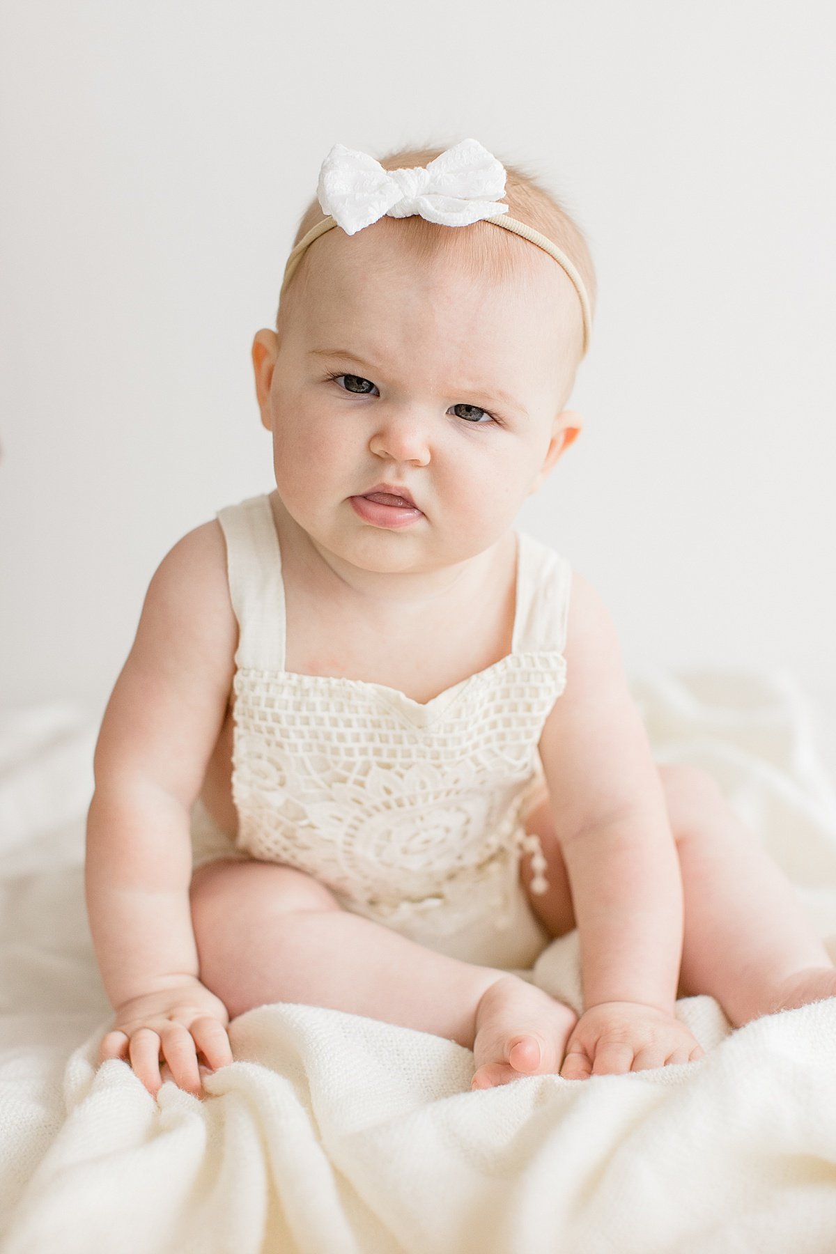 Baby girl making silly face during milestone studio portrait session | Ambre WIlliams Photography in Newport Beach Studio