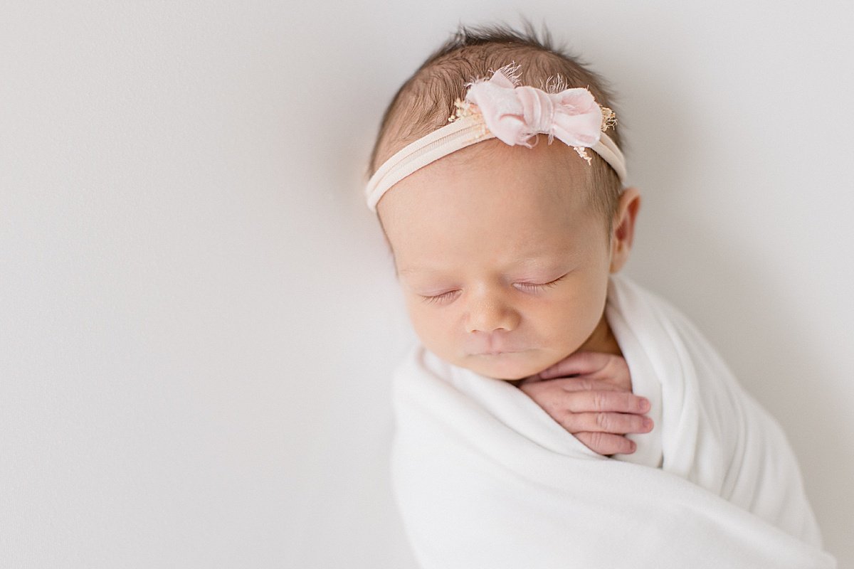 Sleepy baby girl swaddled up during newborn portrait session with Ambre Williams
