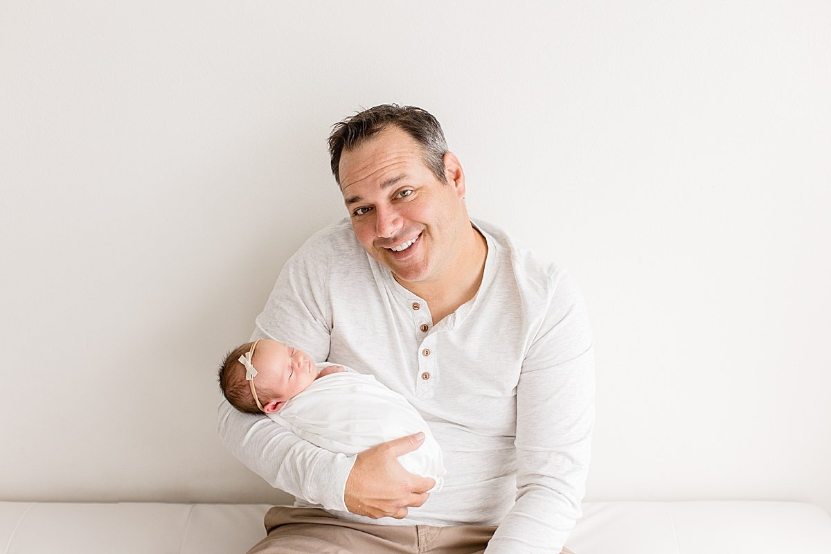 Dad smiling with newborn daughter with Ambre Williams Photography in Newport Beach Studio