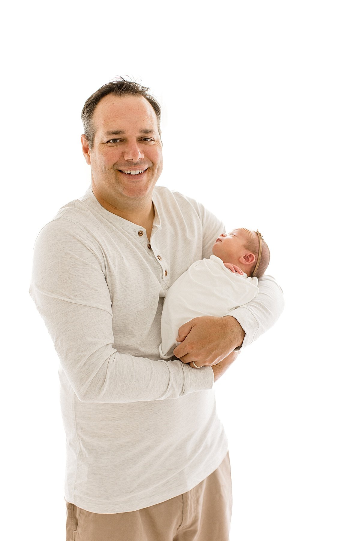 Happy Dad holding his new daughter in his arms during Newborn Photography Session in Newport Beach Studio with Ambre Williams Photography