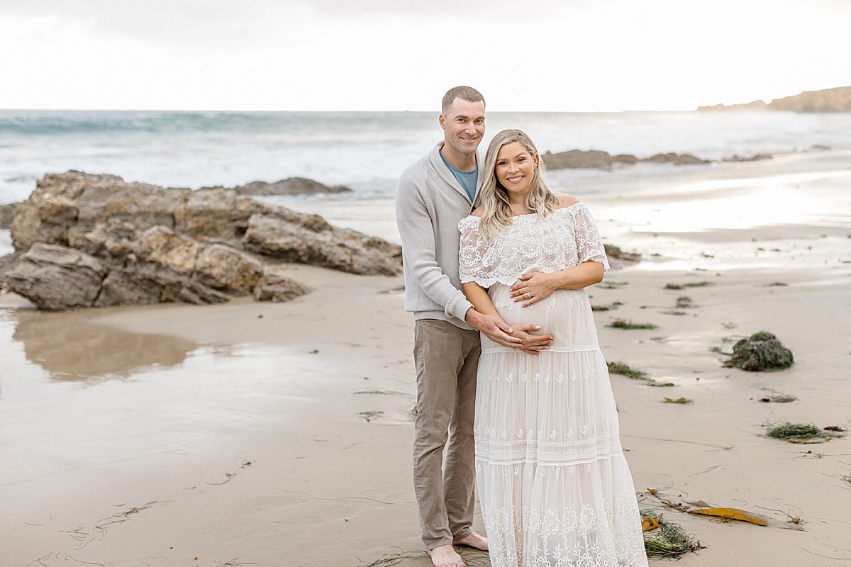 Photographer Ambre Williams photographs husband and wife during outdoor maternity session on beach in california