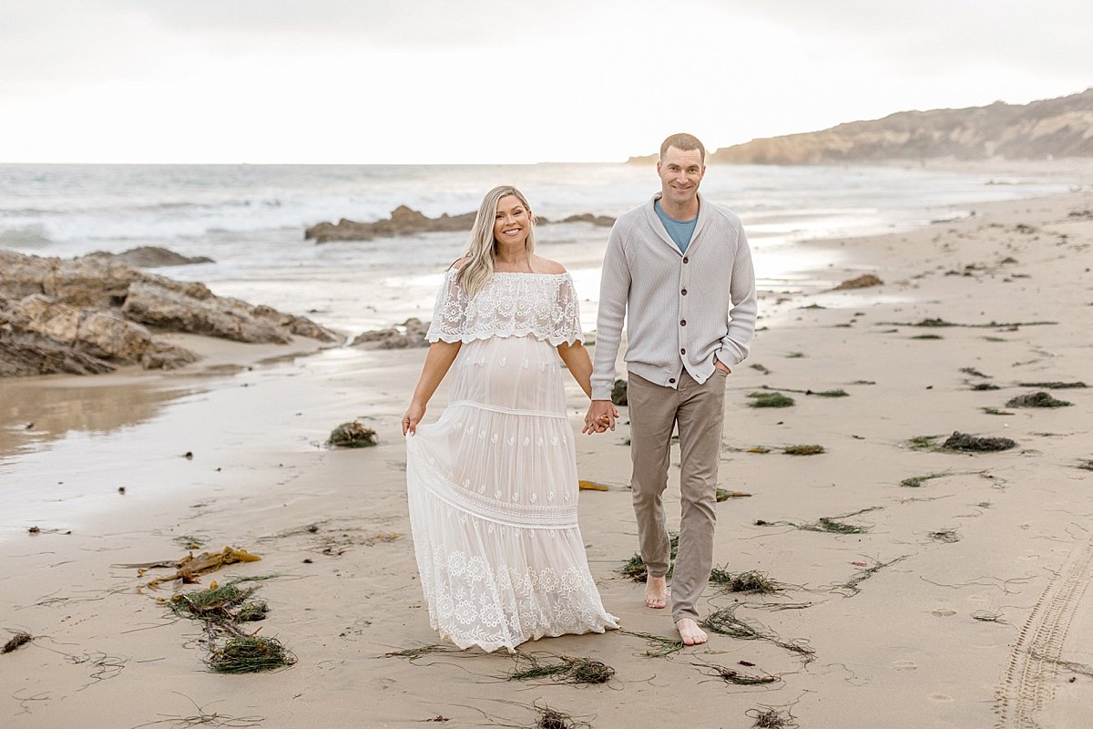 Husband and Wife walking together during outdoor maternity session with Ambre Williams Photography at newport beach