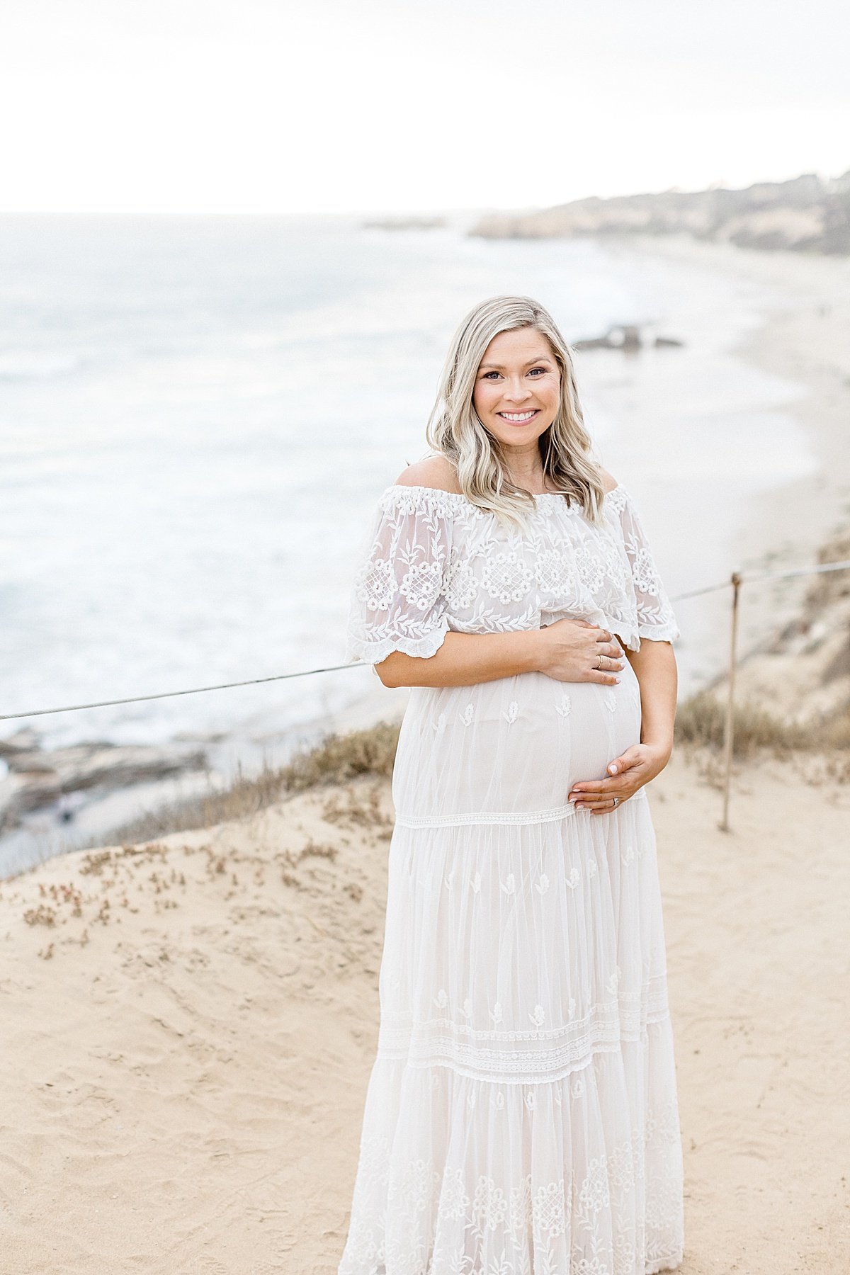 Happy mom-to-be smiles while holding her belly in maternity session with Ambre Williams Photography