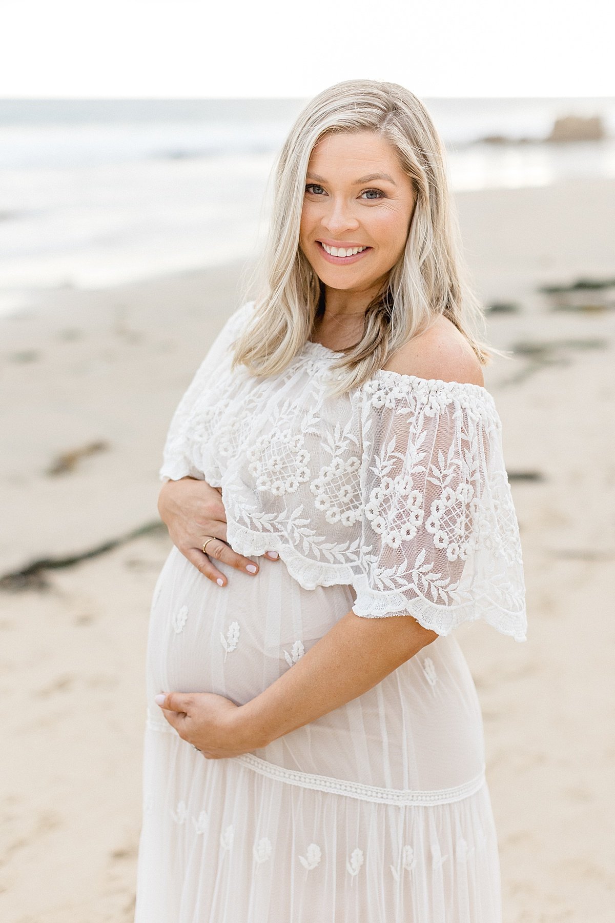 Beautiful smiling momma holding pregnant belly during maternity portrait session | Ambre Williams Photography in Newport Beach, CA