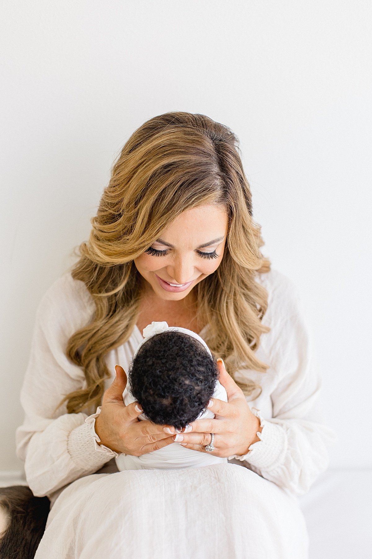 Beautiful Mom smiling at newborn daughter | Ambre Williams Photography in Newport Beach California Studio