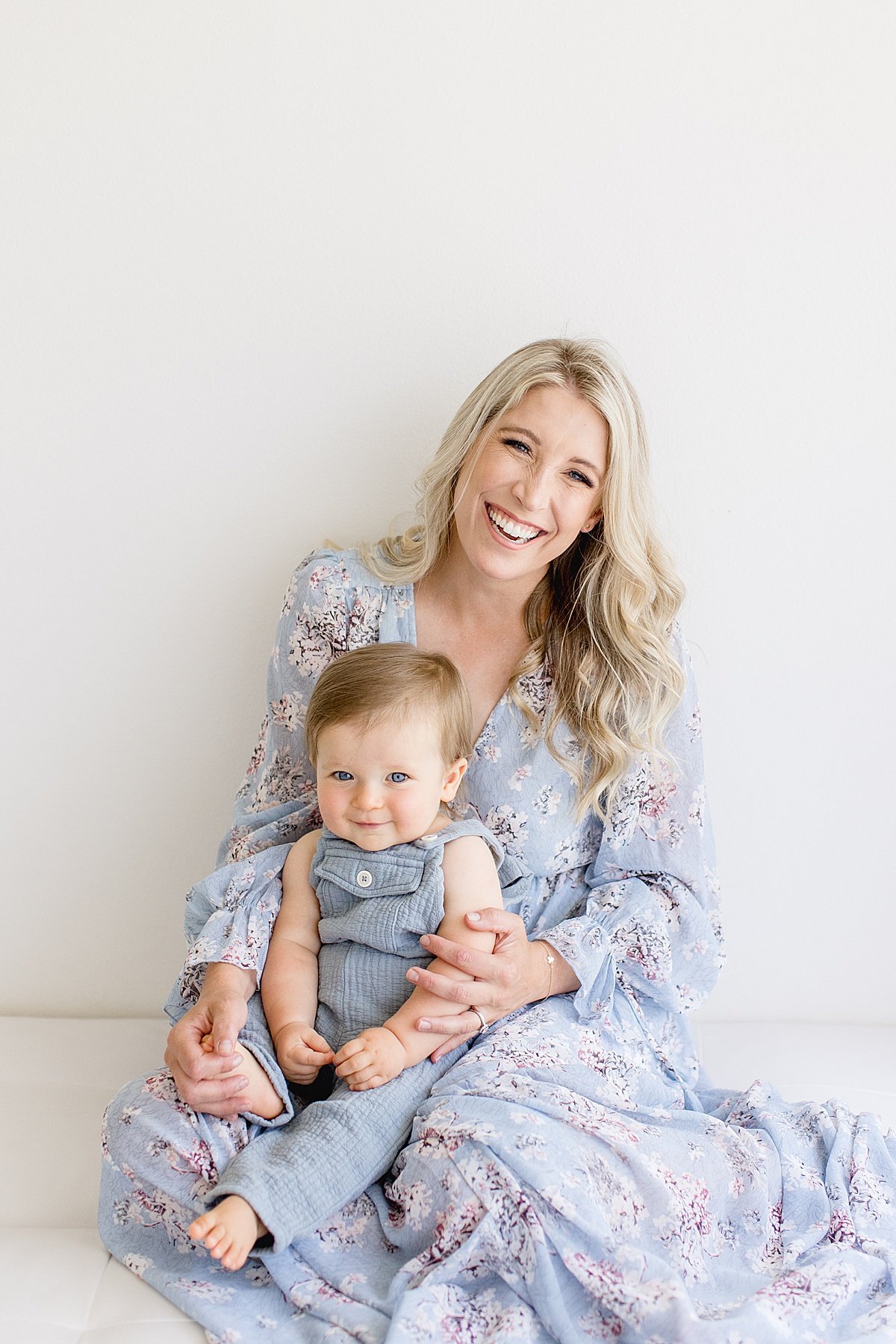 Happy beautiful mama smiling with her baby son during first birthday portrait session with Ambre Williams Photography in studio at Newport Beach