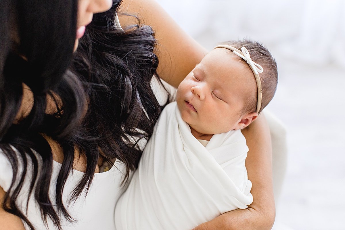 Beautiful Mama holding newborn Daughter during portrait session with Ambre Williams in her studio at Newport Beach, California