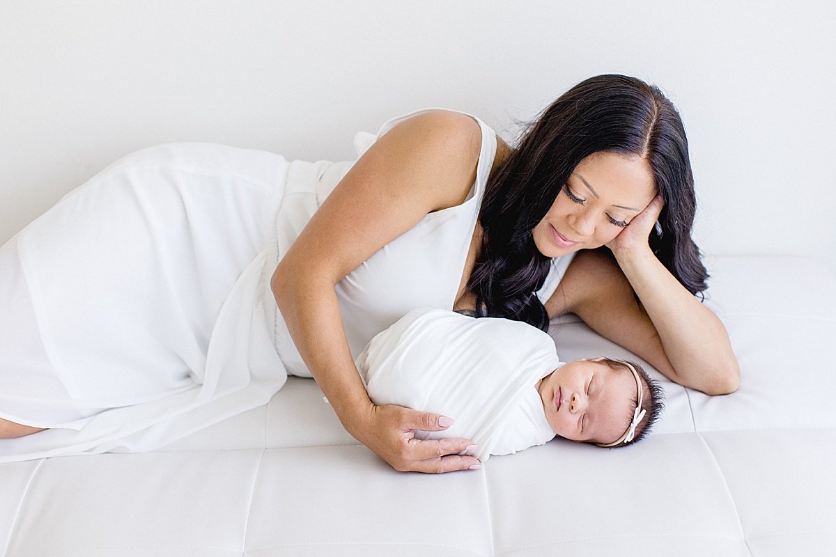 Mama laying down with her baby daughter during newborn session with Ambre Williams in Newport Beach