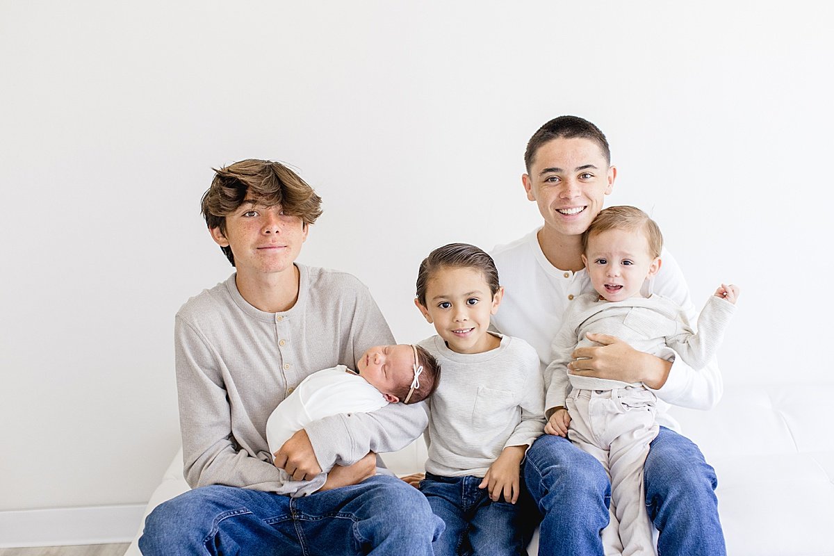 Brothers holding their newborn baby sister during Portrait Session with Ambre Williams Photography in California Studio