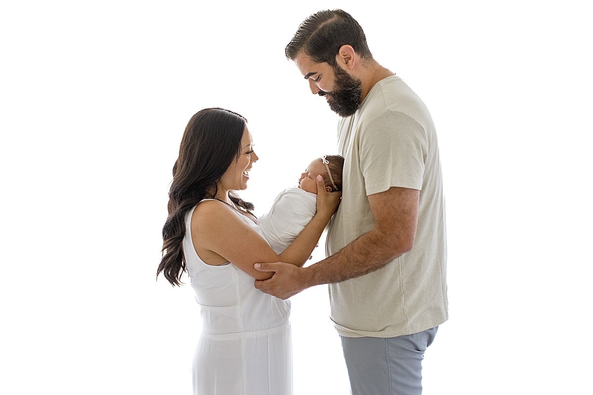 Mom and dad holding newborn baby girl at Ambre Williams Photography in Newport Beach