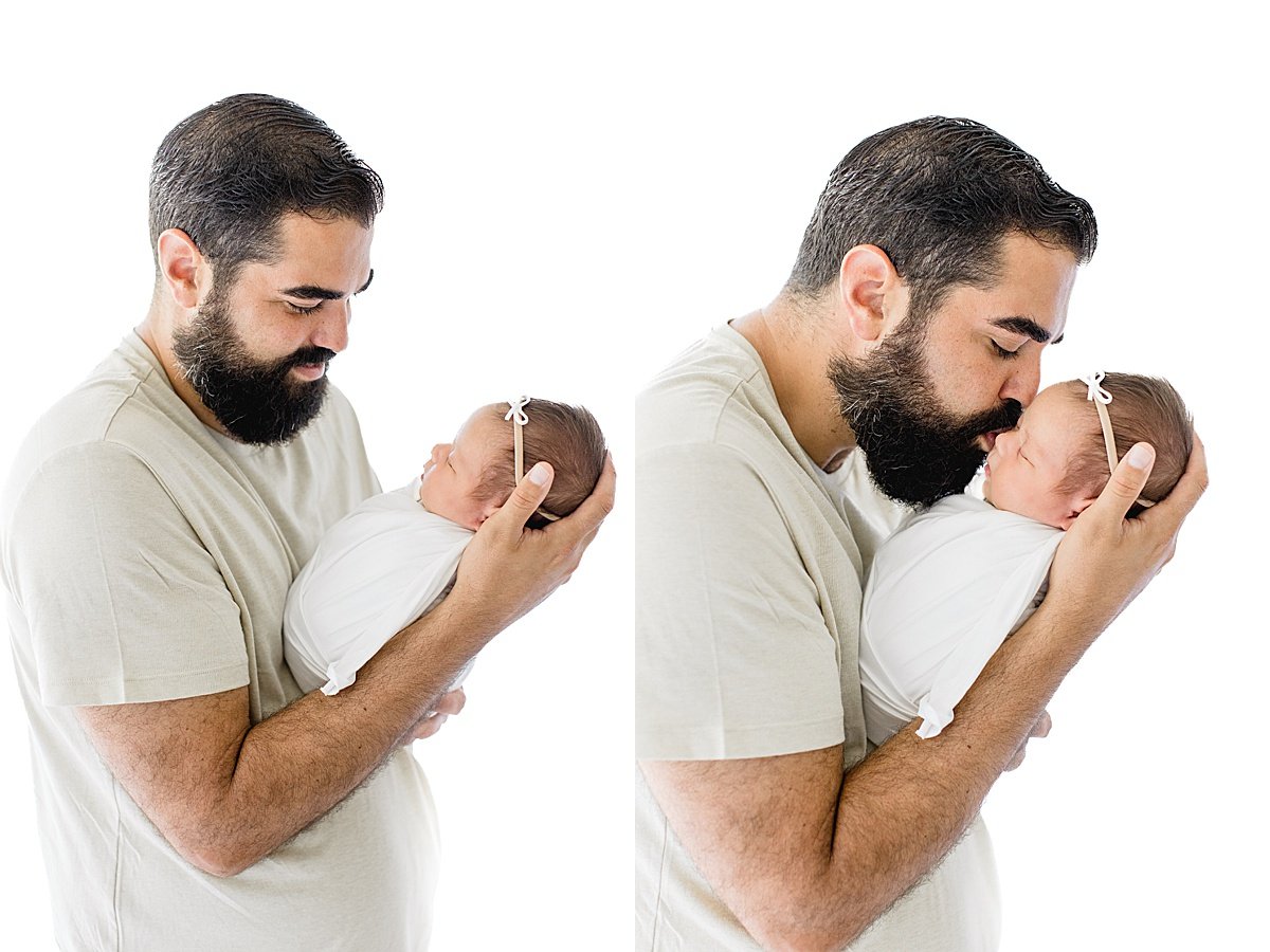 Dad kissing her newborn baby daughter during portrait session with Ambre Williams Photography in California