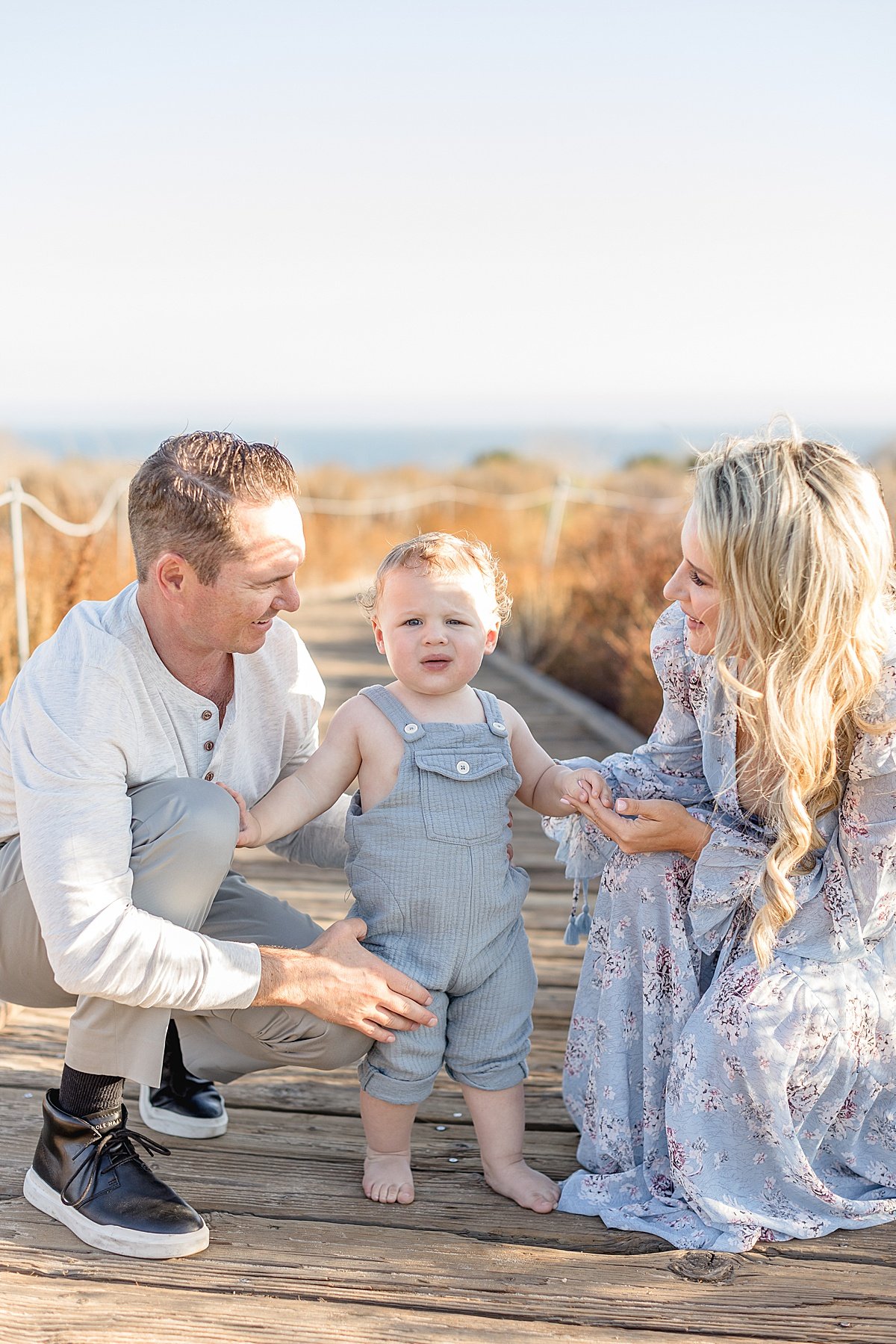 Candid family photo with Mom, Dad, and their little son at the boardwalk on the Newport Beach with Ambre Williams Photography