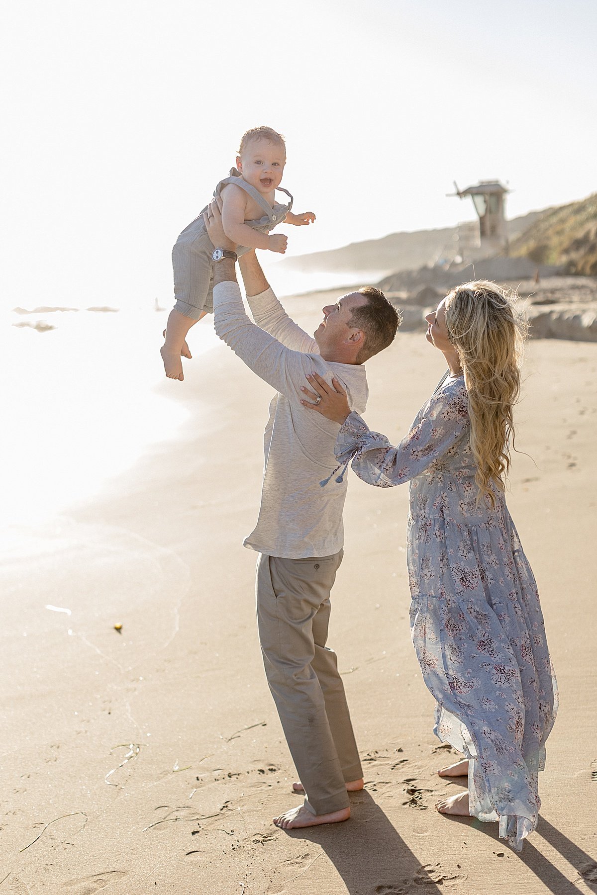 Candid photo of family portrait with Mom and Dad and baby boy during sunset photography session in Newport Beach