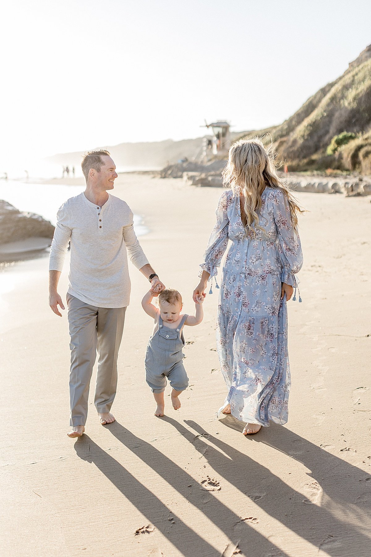 Mom and Dad walking on the beach with their son during portrait sunset session with Ambre Williams on Newport Beach