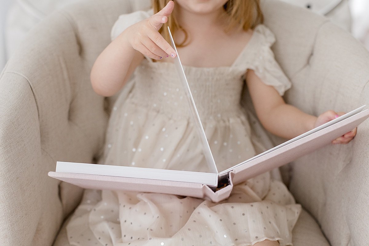 Small child flips through heirloom photo album of family | Ambre Williams Photography in Newport Beach Studio