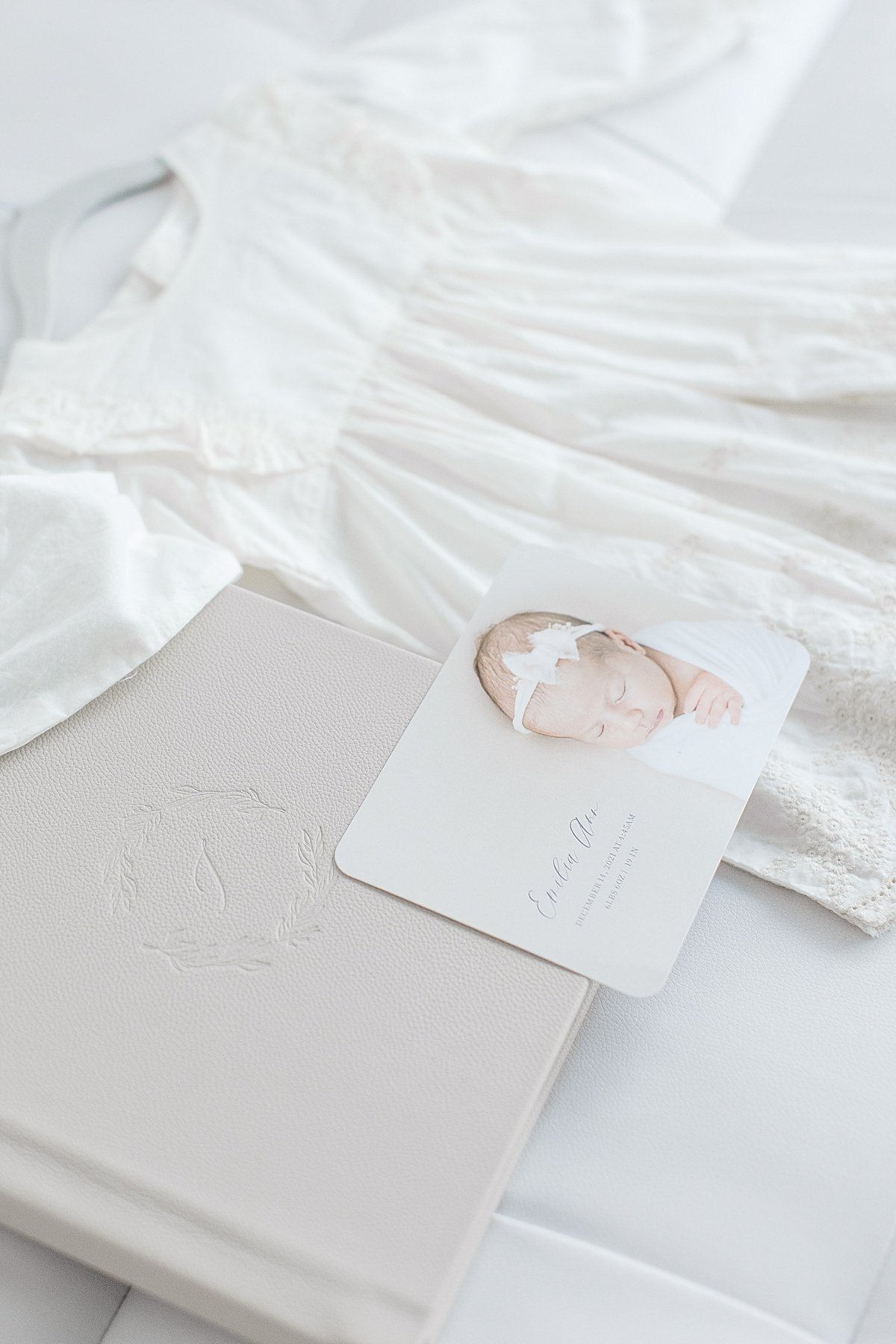 Heirloom Photography Album flat lay with newborn baby announcement and little white dress | Ambre Williams Photography Newport Beach CA