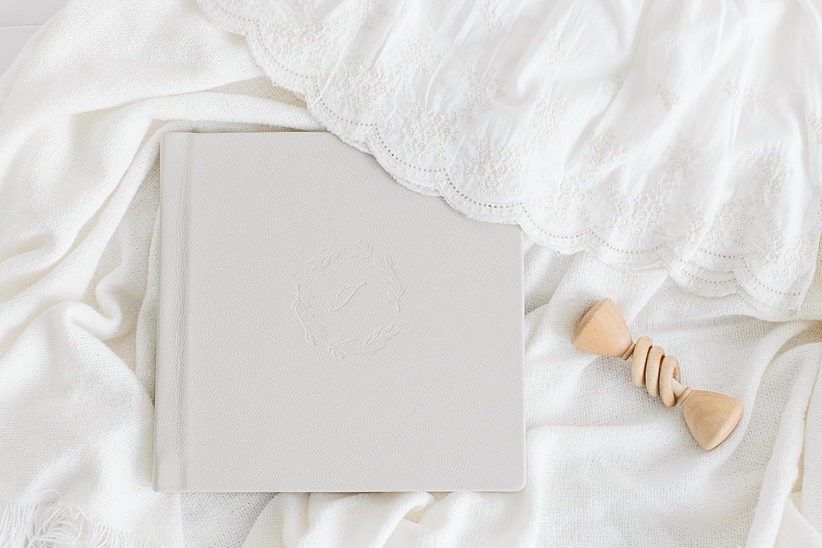 Flat Lay of beautiful grey canvas family photo album on top of white covers | Ambre Williams Photography in Newport Beach Studio