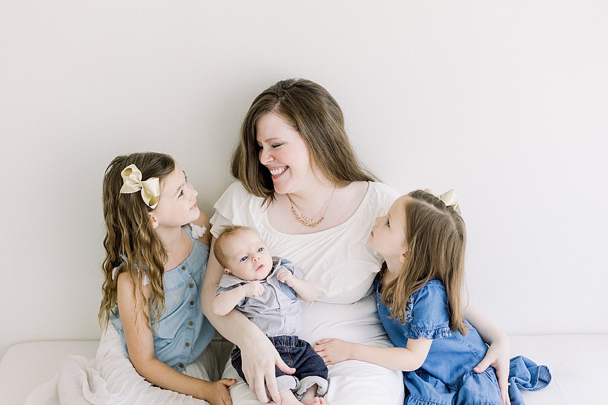 Mom and Daughter smiling while holding baby boy son | Portrait Session with Ambre Williams Photography in Newport Beach