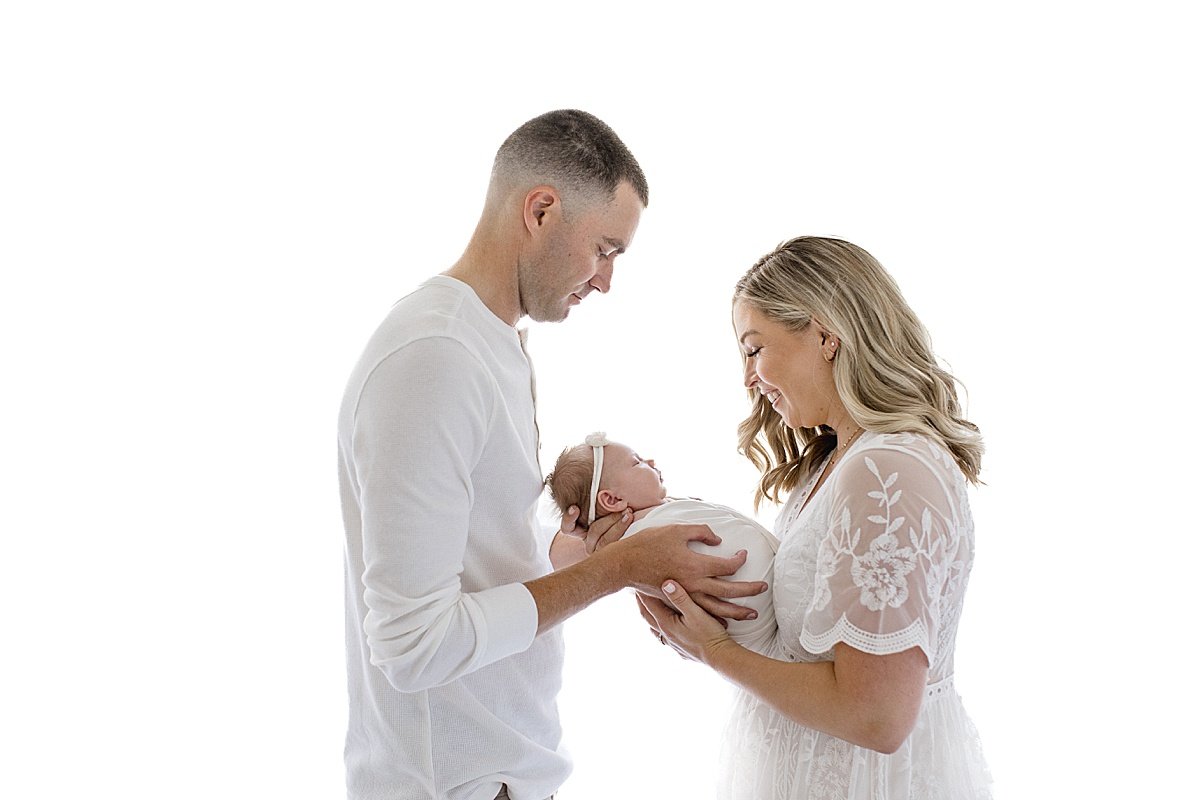 New parents holding their newborn baby girl during portrait session with Ambre Williams Photography in her photography studio in Newport Beach