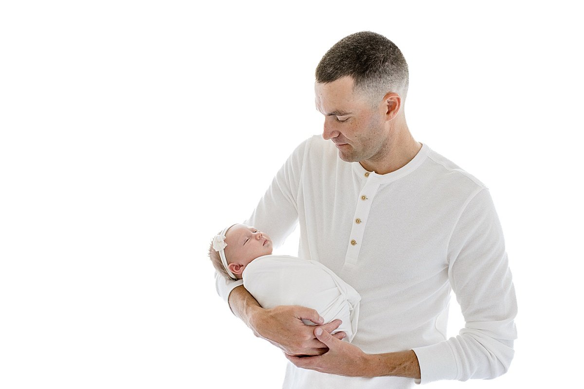 Dad holding his newborn daughter during signature portrait session with Ambre Williams Photography in Newport Beach California