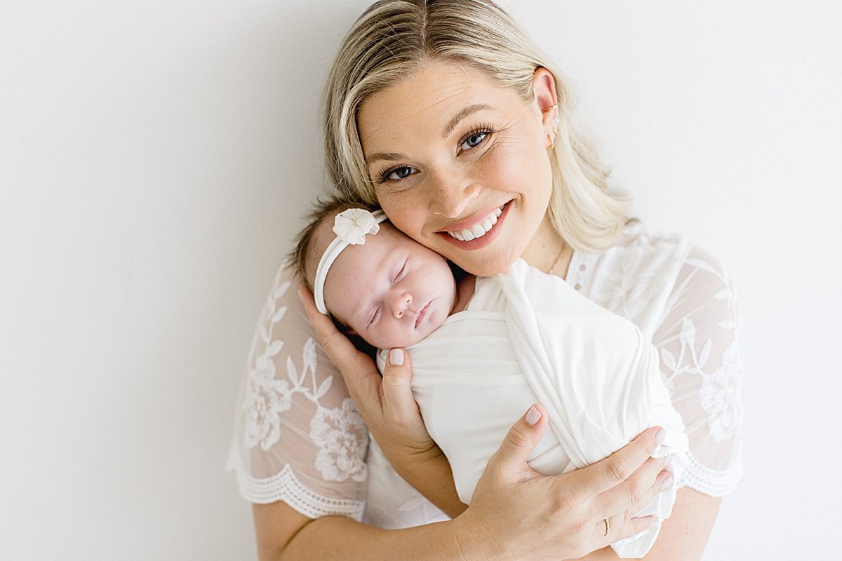 beautiful momma holding her newborn baby girl smiling at camera during portrait session with Ambre Williams Photography