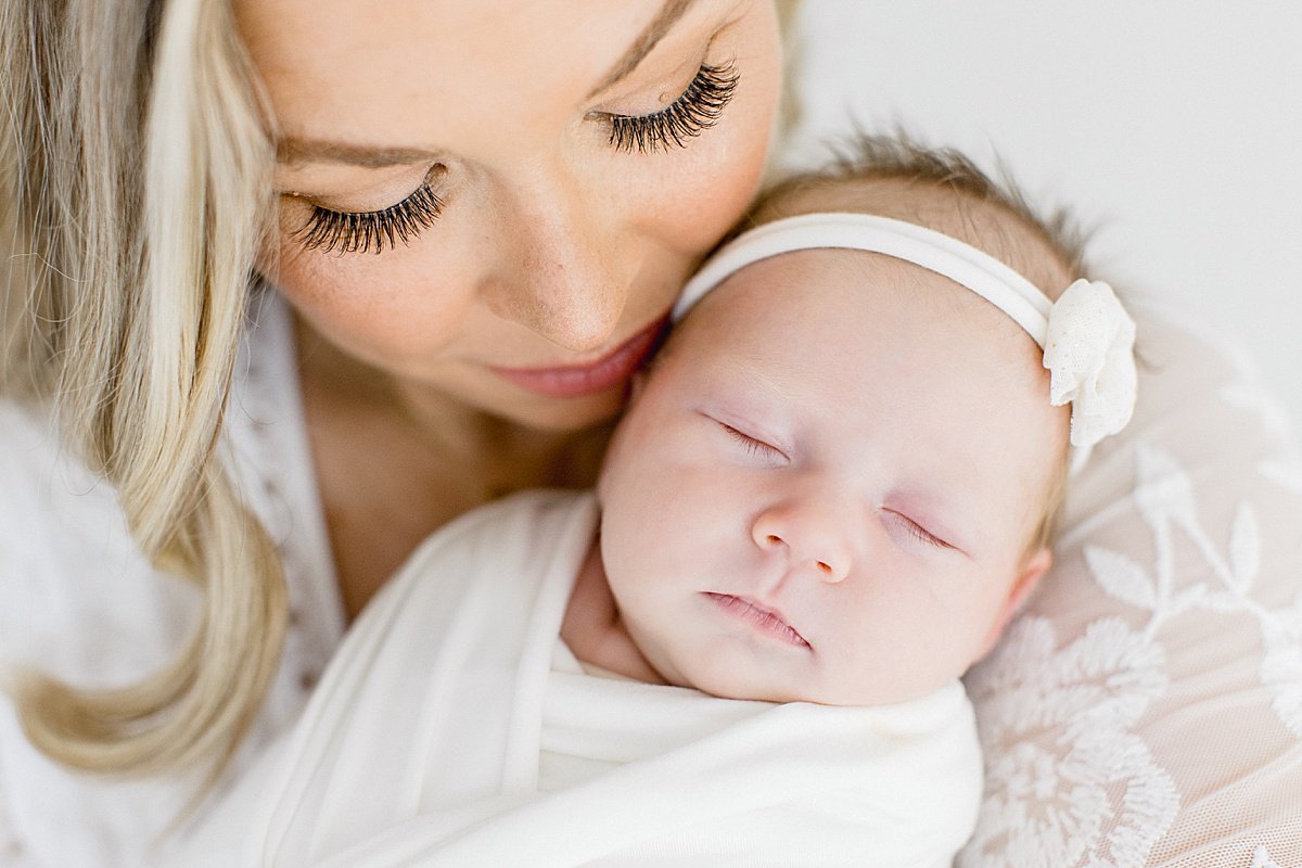 Close-up of mom kissing her newborn baby daughter during portrait session in Newport Beach California