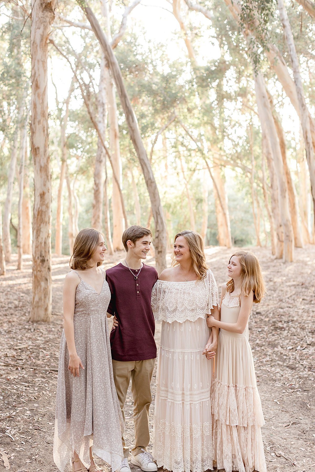 Mom posing with her three children during portrait session outdoors with Ambre Williams Photography in Newport Beach