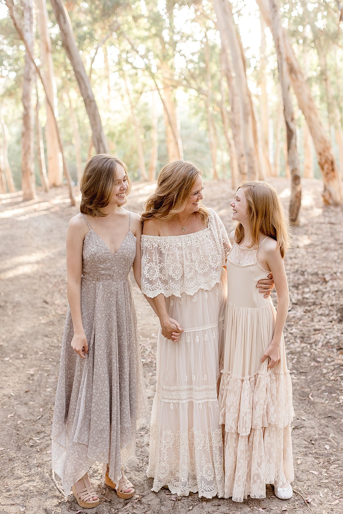 Mom and her two daughters smiling at each out candid during portrait session with Ambre Williams Photography