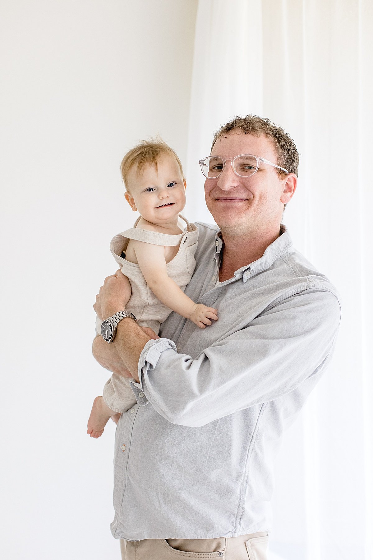 Dad and baby son smiling together during 1 year old portrait session with Ambre Williams in studio at Newport Beach